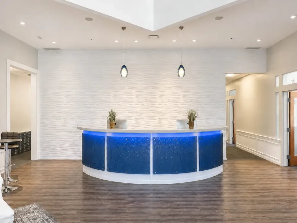 Lobby with a curved desk, blue accent lighting and a textured white feature wall at Seacoast Professional Suites, Portsmouth NH